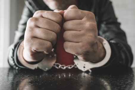 Handcuffed hand is strapped inside interrogation room.